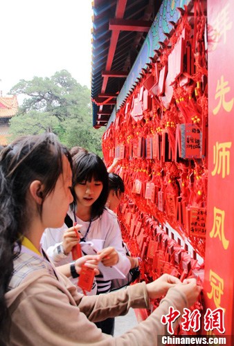 资料图为台湾学生在孔庙大成殿前悬挂许愿牌，祈福自己升学顺利。中新社发 李欣 摄