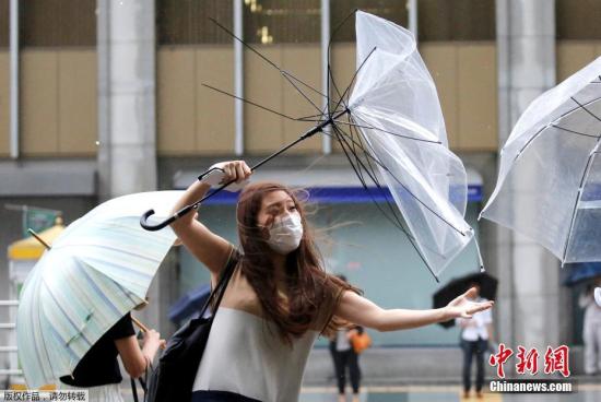 当地时间2018年8月8日，台风“姗姗”逼近日本，东京民众用雨伞抵挡暴雨和大风。因风力过大，街上行人的雨伞在风中呈现各式造型。