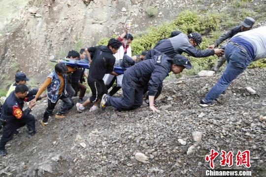 图为民警与民众联合将伤者用担架抬上悬崖。云南省公安厅供图