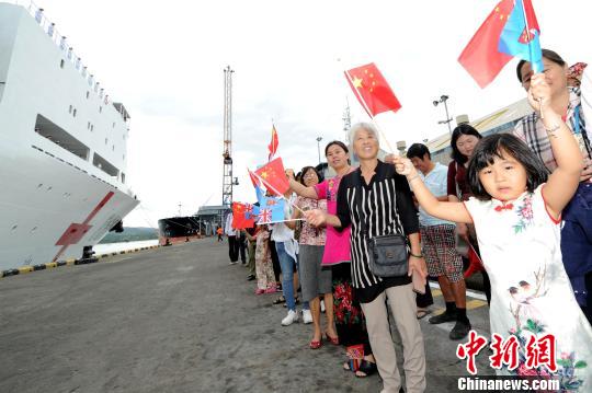 在斐济苏瓦港码头，一名小朋友挥动中斐两国国旗，为中国海军和平方舟医院船送行。　江山 摄