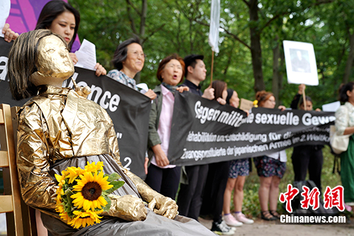 图为当天下午，抗议者在德国柏林的日本驻德大使馆前摆放象征受害者的塑像并表达诉求。中新社记者 彭大伟 摄