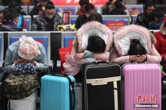 2月1日，三位旅客正趴在行李箱上休息。当日，为期40天的2018年春运正式启幕，浙江杭州铁路直属站(包括杭州东站)迎来大量出行客流。中新社记者 王远 摄