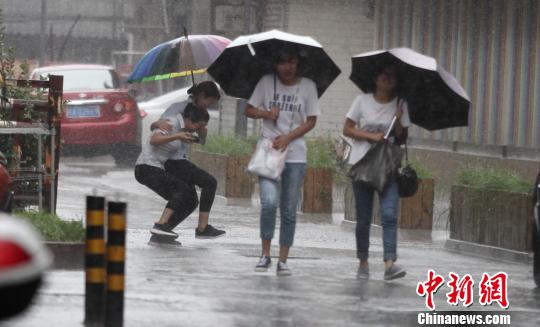 图为扬州风大雨急，民众艰难出行。　孟德龙　摄