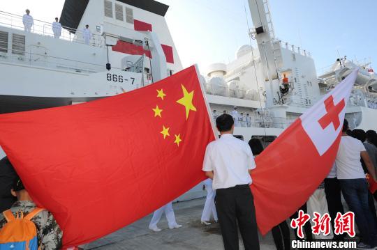 8月20日，在汤加努库阿洛法港码头，华侨华人挥动中汤两国国旗为中国海军和平方舟医院船送行。　江山 摄