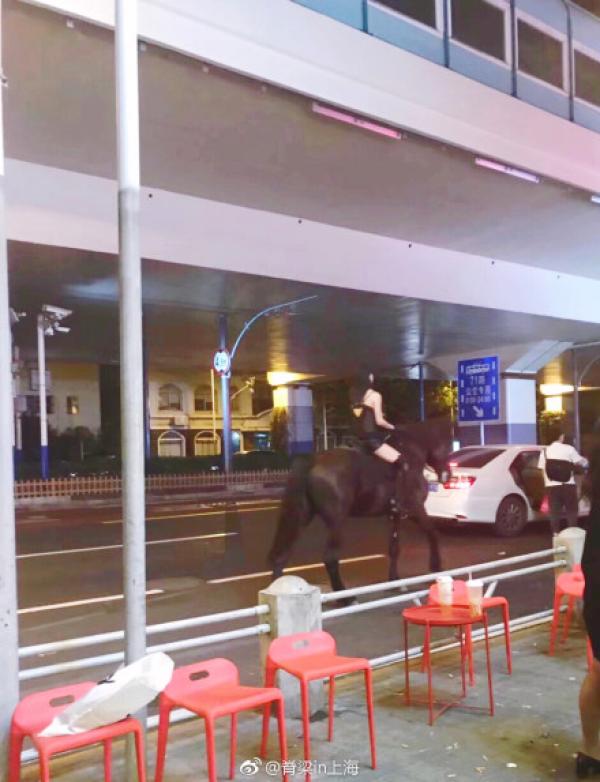 穿吊带的美女骑马穿行上海闹市区