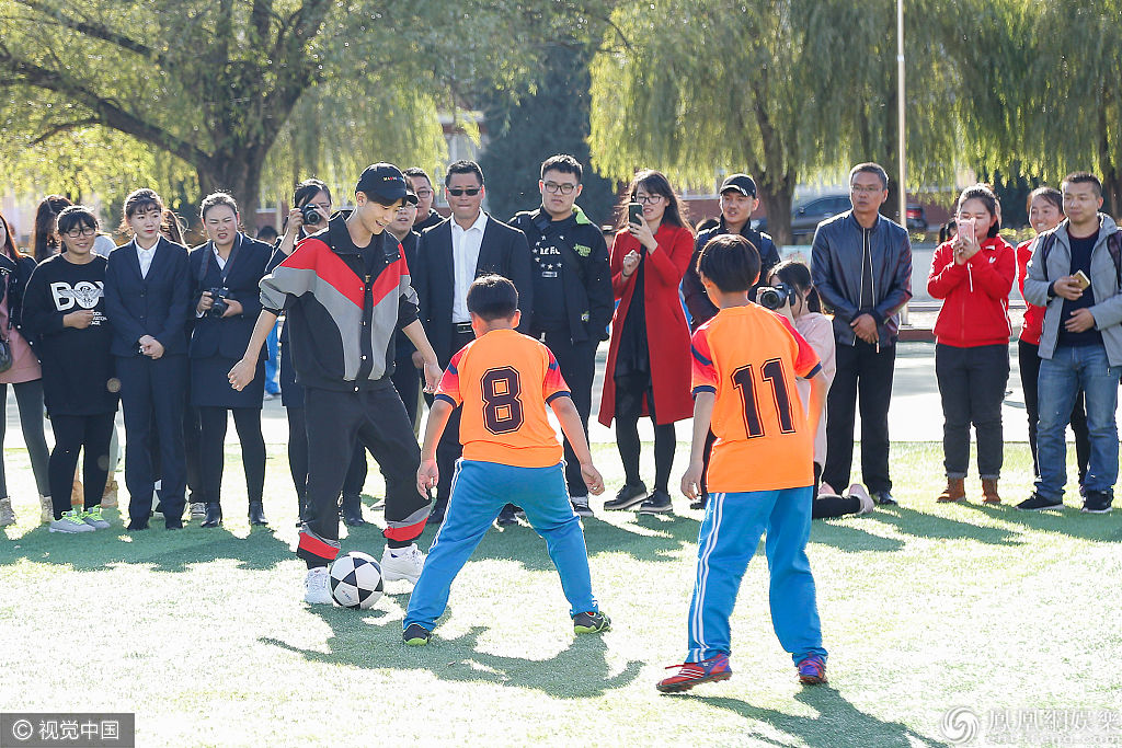 张一山践行公益和小学生切磋球技 踢球摔倒自