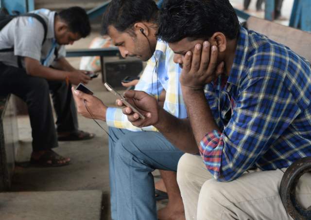 　　图为2016年8月22日在印度孟买，当地人用手机上网。（图片来源：新华社/法新）