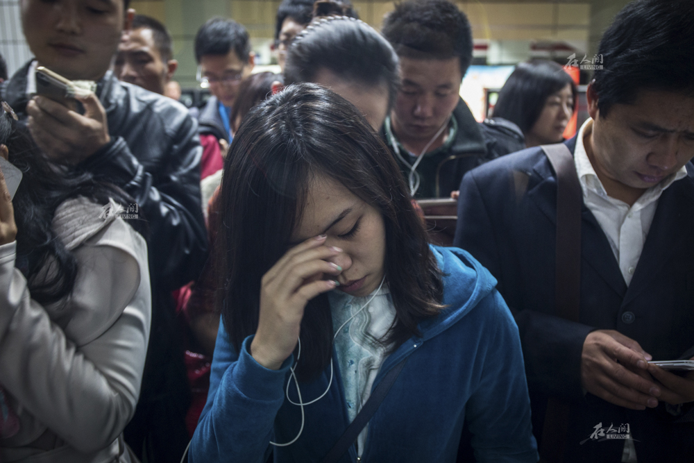 2014年10月13日,地铁里的上班族"统一"低头划拉手机.