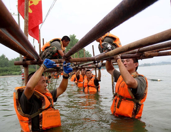 7月18日,江西湖口县,抗洪官兵在齐腰深的水中架设简易桥钢管.