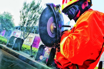 消防队员正在展示用电锯割断铁丝但不伤灯泡的绝活 摄/记者 曹博远