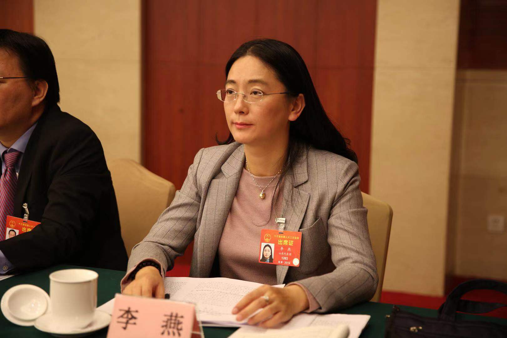 山东舒朗服装服饰股份有限公司董事长吴健民一边听政府工作报告,一边