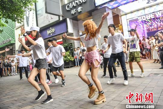 步行街上,十余名年轻的舞者突然出现在人群中,伴随音乐玩起"街舞快闪"