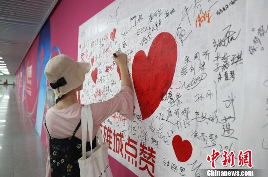 图为一位女子在"天下英雄城"主题彩绘签名墙签字,为英雄城"点赞".