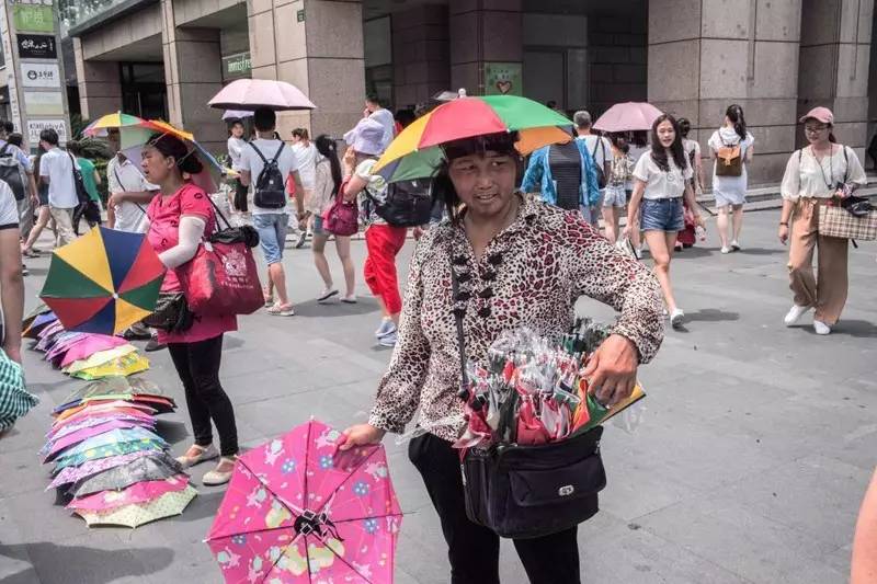 昨天中午,七八个小贩在西湖边平海路口的人行道上摆摊卖伞帽.