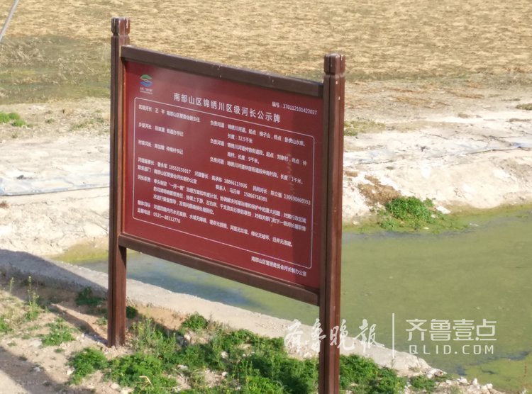 (河道边立着河长公示牌)