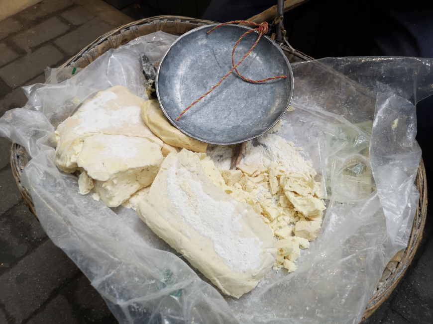 一大块麻糖,卖货郎拿着锤子和小铁锹一点点的敲下来,叮叮当当,声音